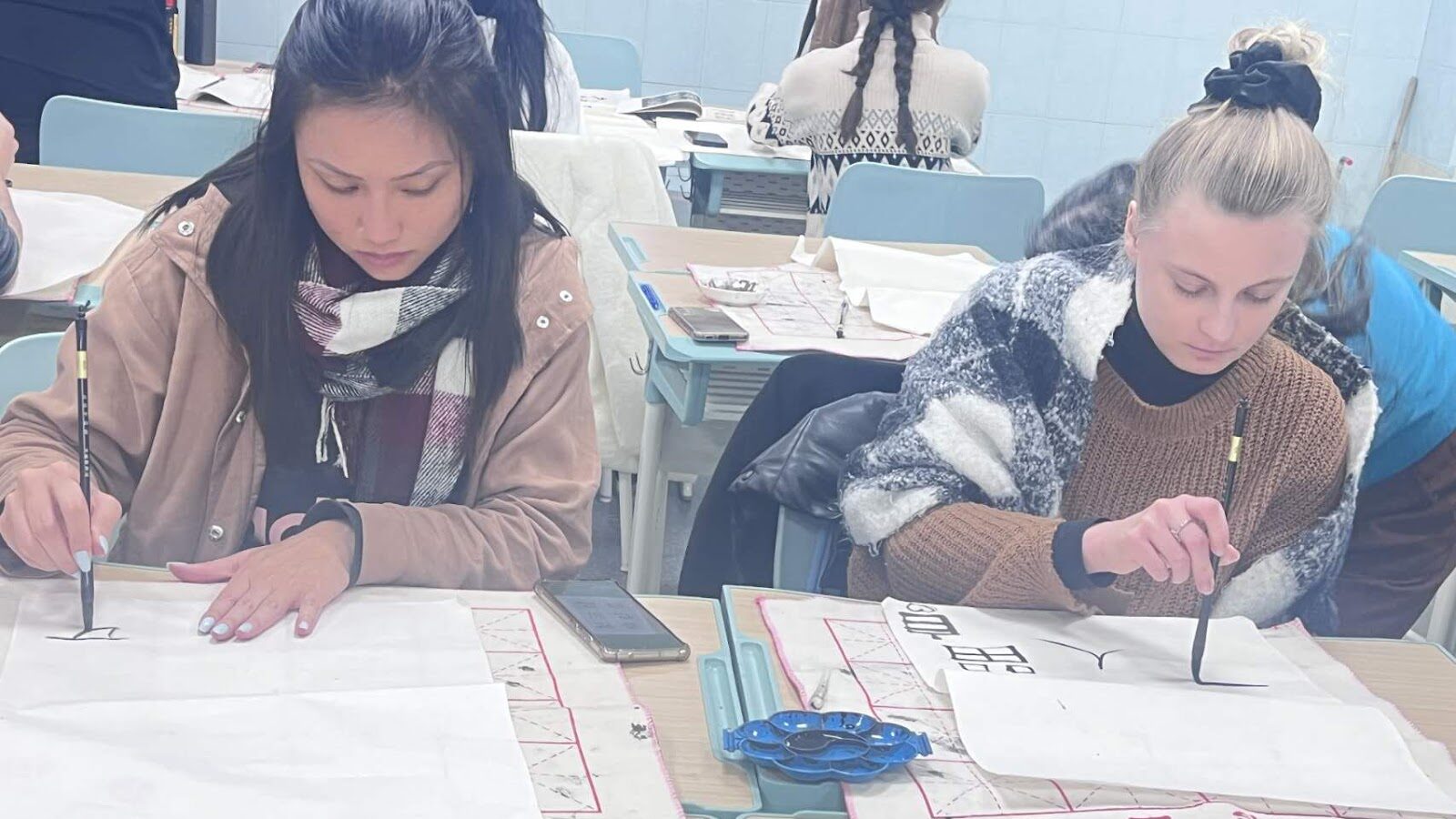 Estudantes de mandarim praticando a caligrafia chinesa. 